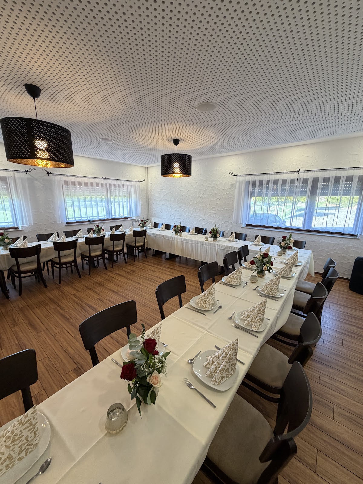 Festlich eingedeckter Saal im Steiner Waldhaus mit langen Tafeln, weißen Tischdecken und Rosen